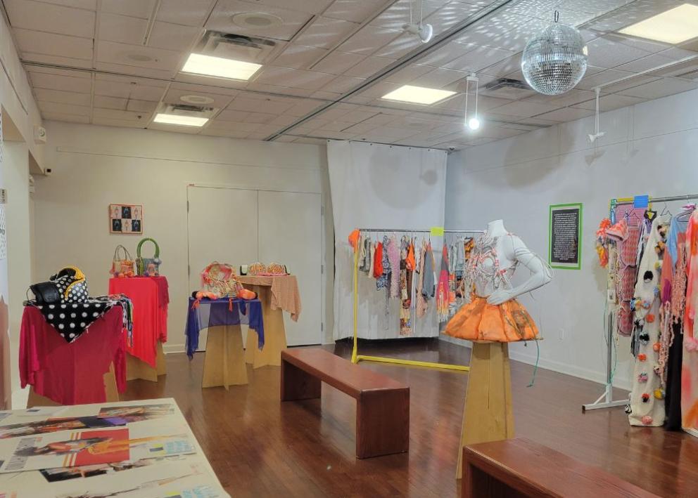 Gallery space filled with various bright clothing items and accessories that are ecofriendly high fashion. 