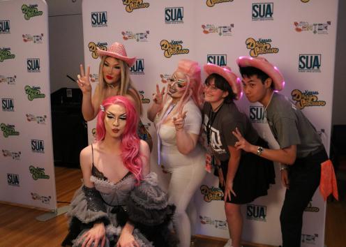 Participants pose with Drag performers at a photo booth