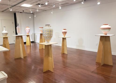 7 various ceramic vases scattered on pedestals in the gallery