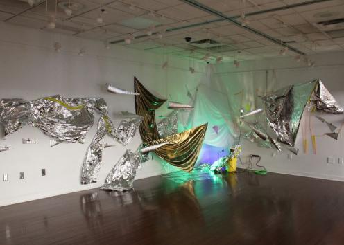 Various pieces of aluminum hanging from the ceiling with a projected green light on the displays. 