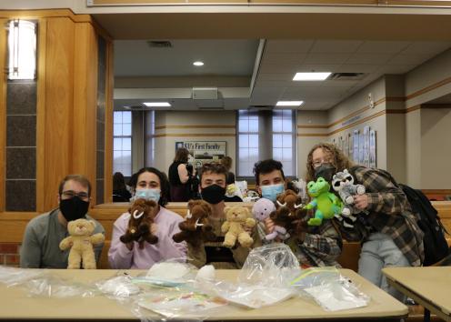 Students showing their stuffed bears in front of Traditions Area